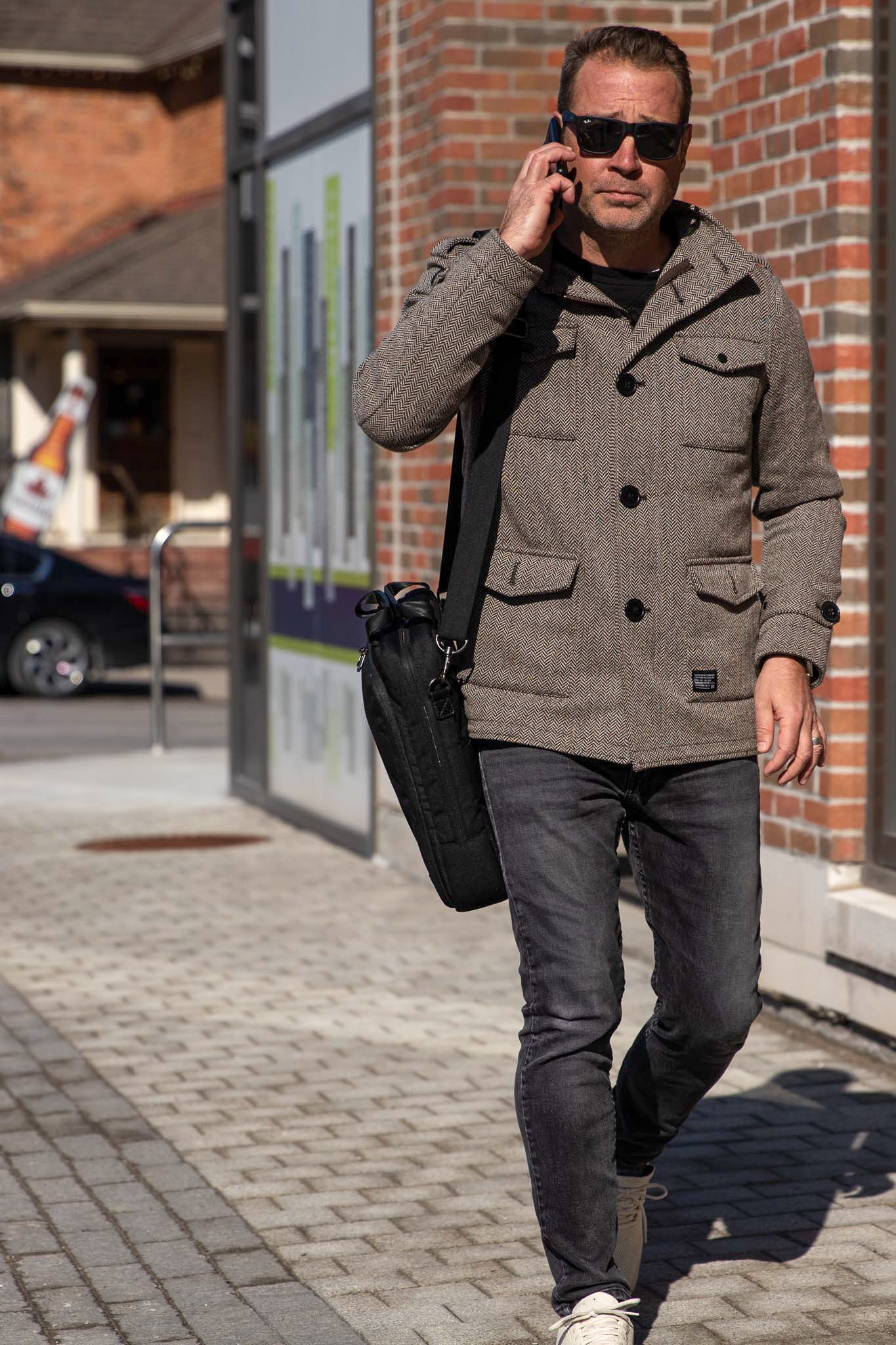 Man walking with PKG Riverdale 11L Messenger Bag on shoulder