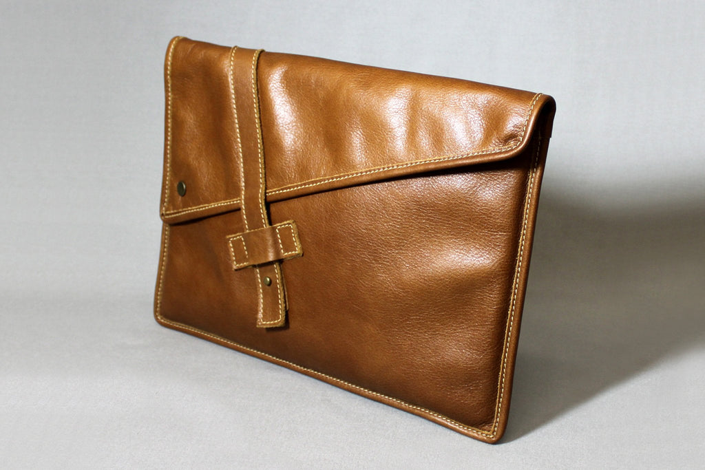 PKG Slim Leather Sleeve 13" (tan). Crafted from distressed top grain leather, this slim laptop sleeve features antique brass hardware, a secure collar tab closure, and a custom snap for added security. Carry it solo or slip into another bag effortlessly