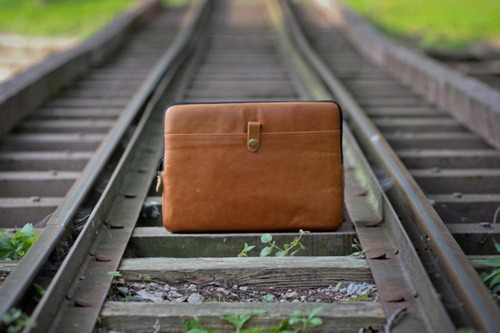 PKG Skinny Leather Sleeve 15" resting on railroad tracks