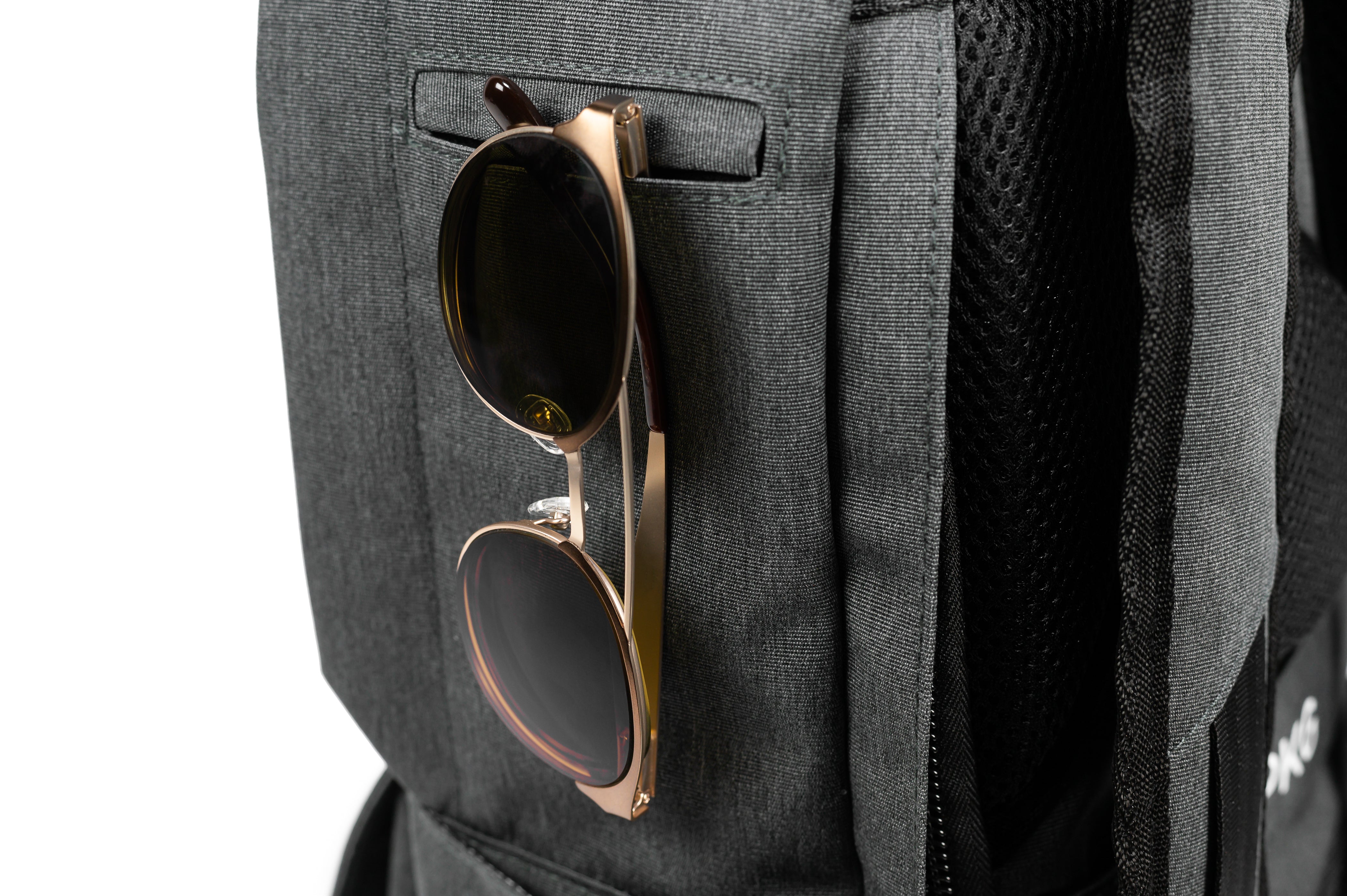 PKG Rosseau 19L Recycled Backpack Tote (grey) showing sunglasses hanging off of dedicated sunglass pouch