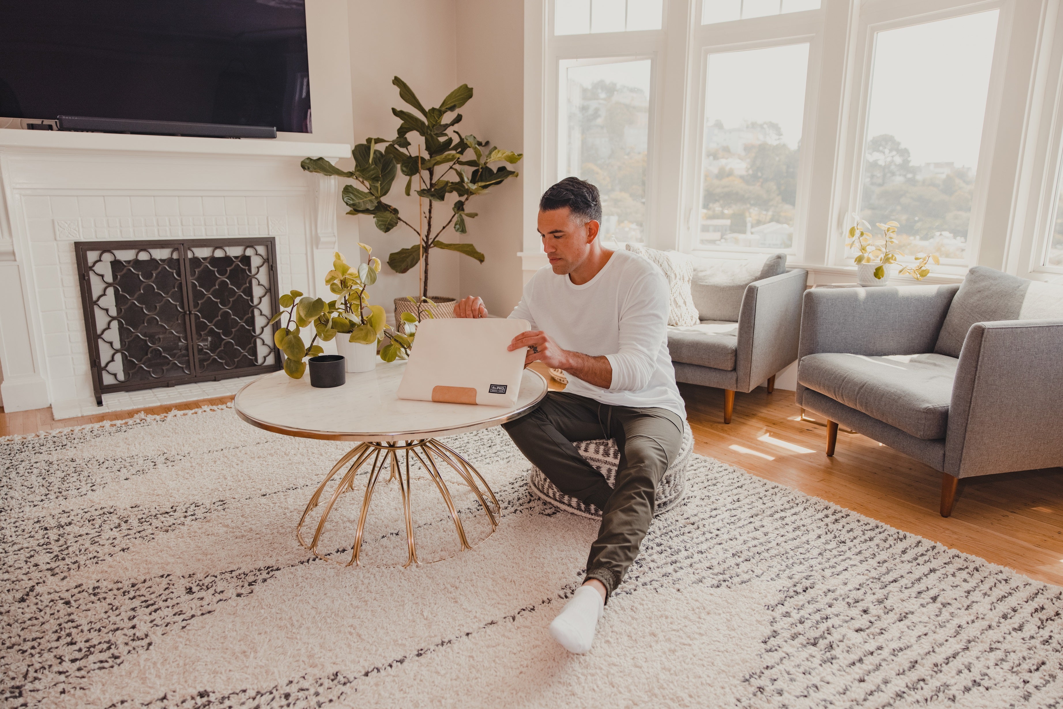 Man using PKG Slouch sleeve (sand) at coffee table