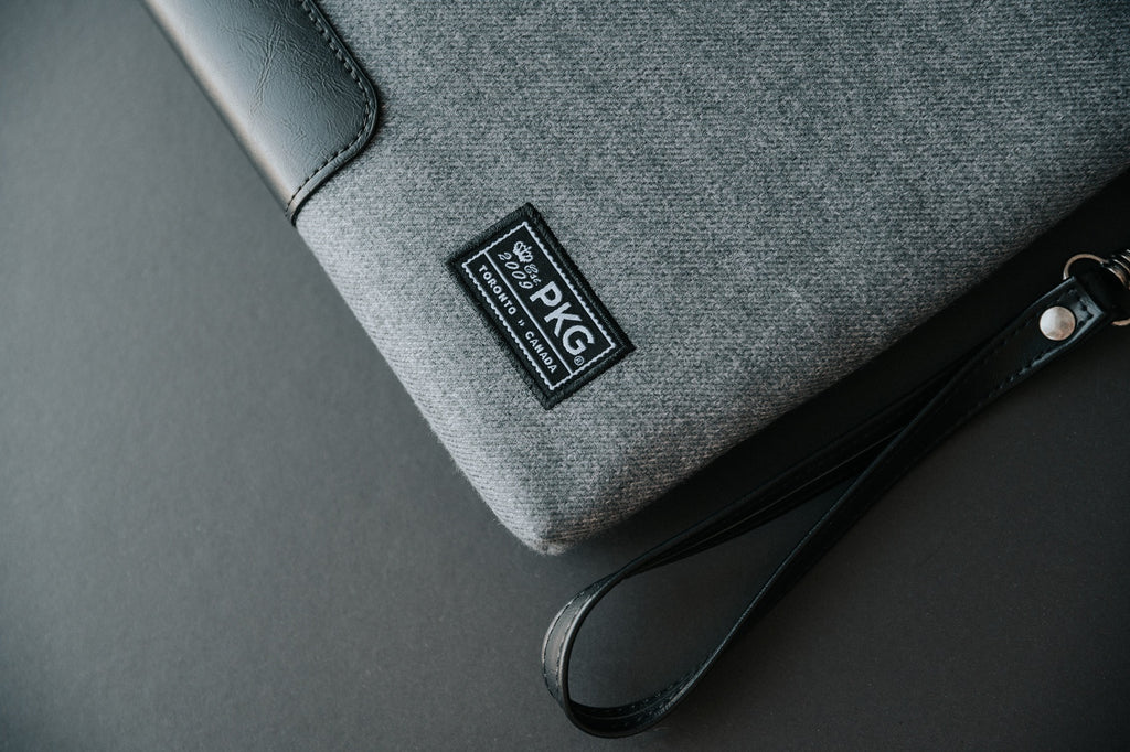 PKG Slouch sleeve (wool grey) detailed view showing logo patch, and vegan leather accents