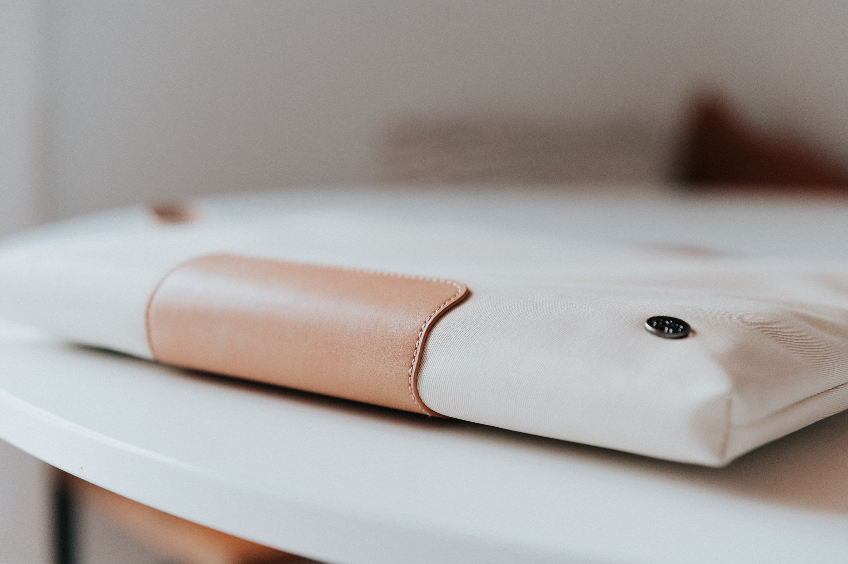 PKG Slouch sleeve (sand) resting on table featuring vegan leather accents