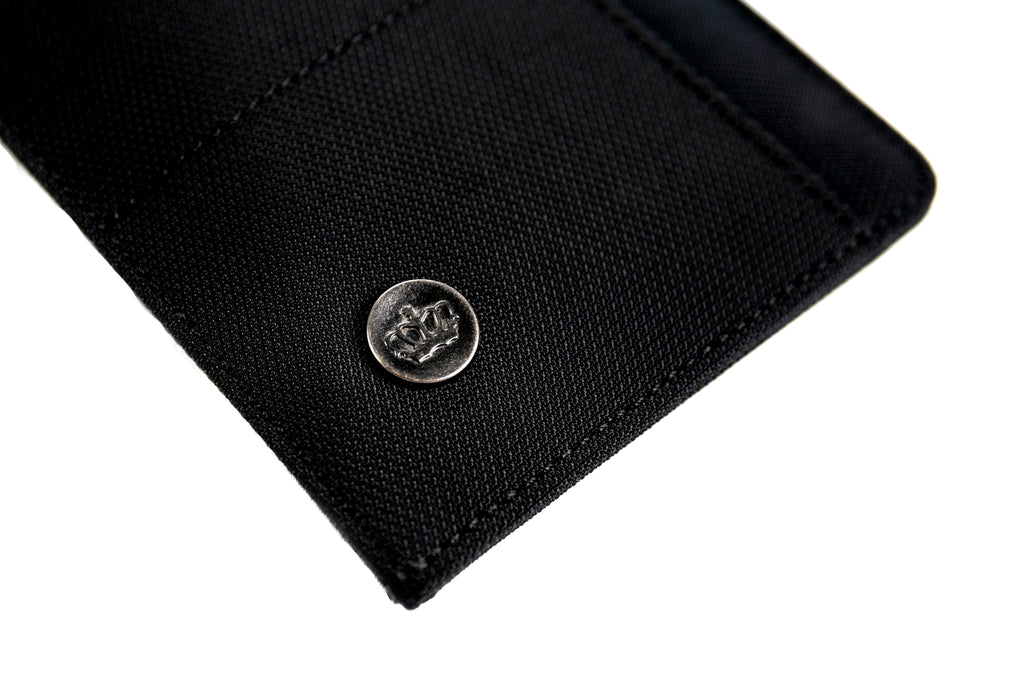 PKG Perry RFID Passport Wallet (black) angled view showing durable material details and pkg insignia
