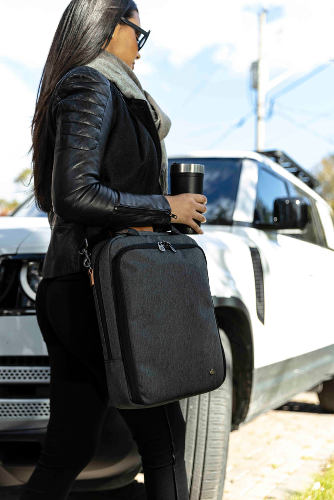 Woman walking to car carrying PKG Riverdale 11L Messenger Bag on shoulder