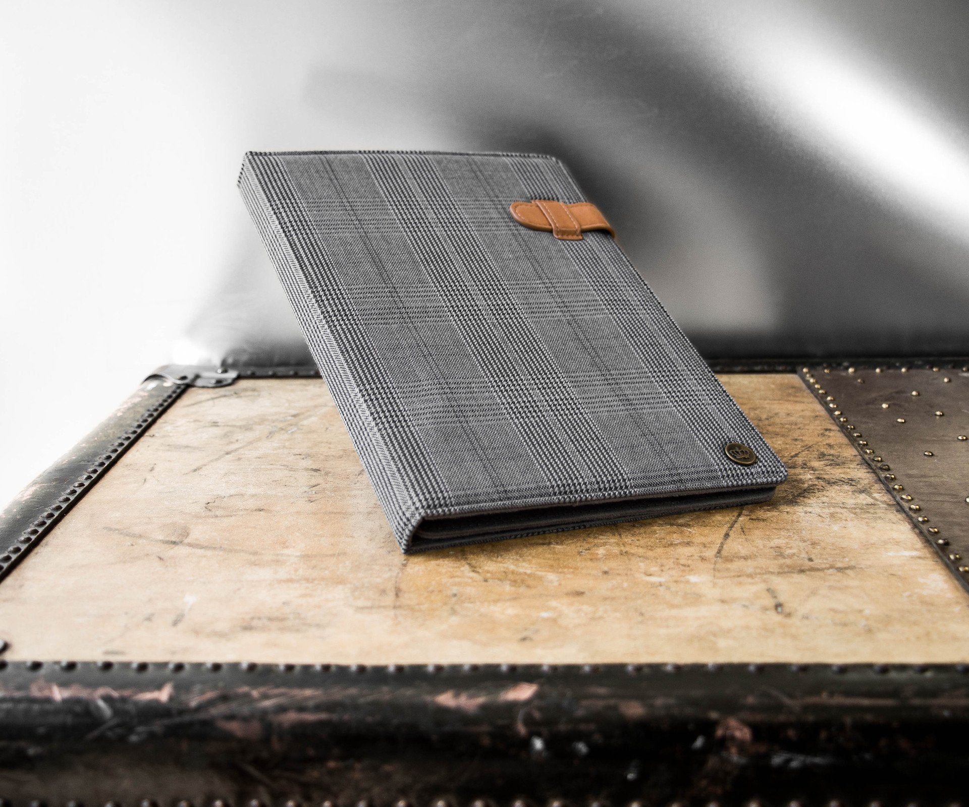 Universal Tablet Folio (plaid black) resting on backdrop